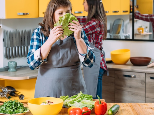 Two women in kitchen cooking Mother smelling lettuce with eyes closed Selecting choosing healthy organic ingredients