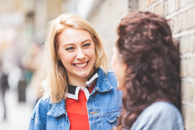 Photo two women leaning on a wall and talking in london