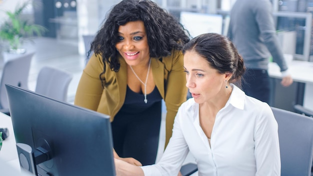 Two women looking at a computer screen, one of them is looking at a screen that says'it's time to get it '