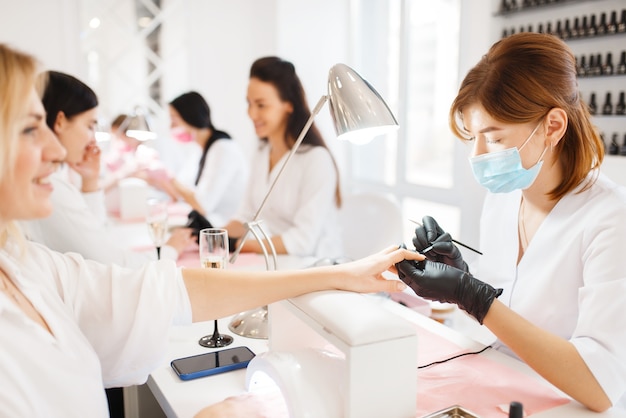 Two women on manicure procedure, beauty salon