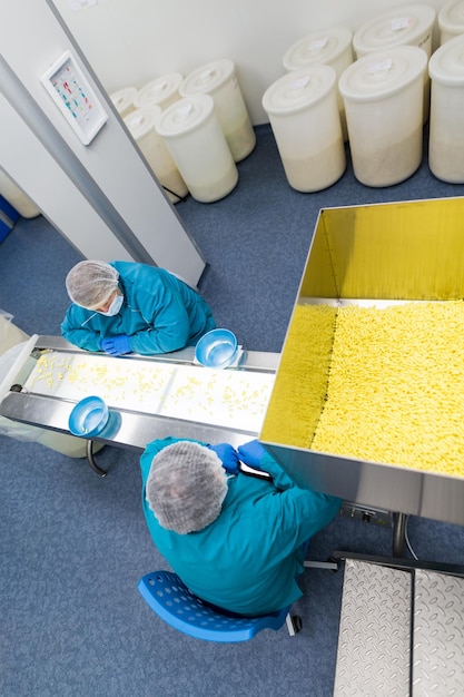 Two women in medical suits working on conveyor