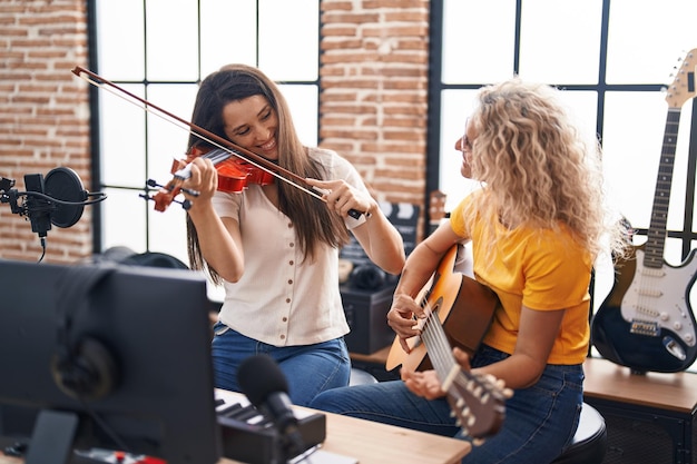 Two women musicians playing violin and classical guitar at music studio