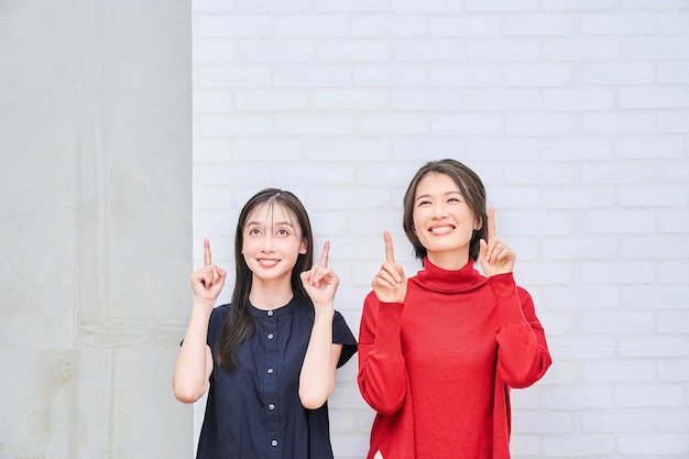 Two women pointing upwards indoors