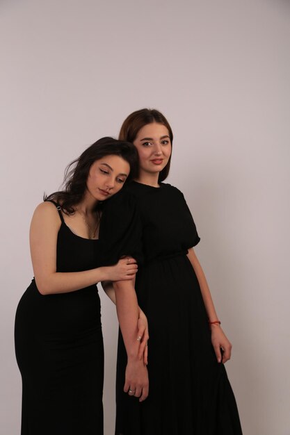 two women pose for a photo in a black dress