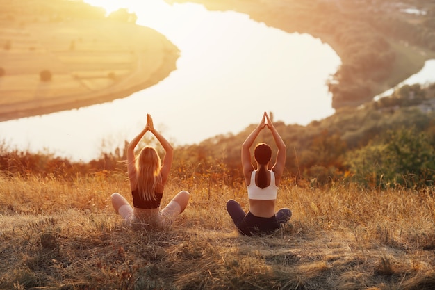 Две женщины практикуют йогу и медитацию на горе. Они медитируют на высокой горе