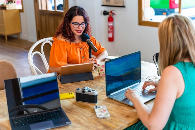 Two women recording a podcast in a collaborative office