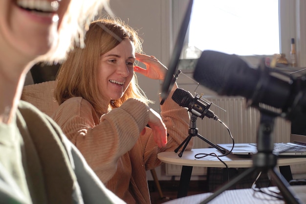 Two women recording podcast laughing at home