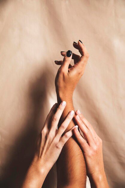 Two women's hands take care of and caress the arm of a black woman on a background of satin fabric Union diversity community sisterhood