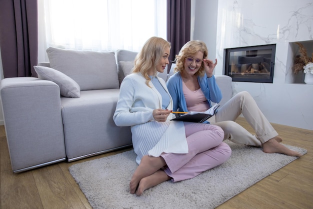 Two women sitting on the carpet in the living room