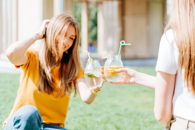 two women sitting on the grass with lemonade cocktails