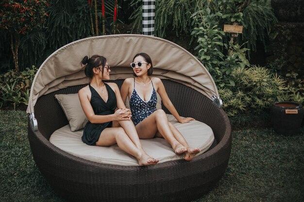 Two women sitting on a round chair in a garden