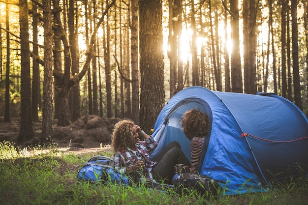 Two women sitting in tent at forest