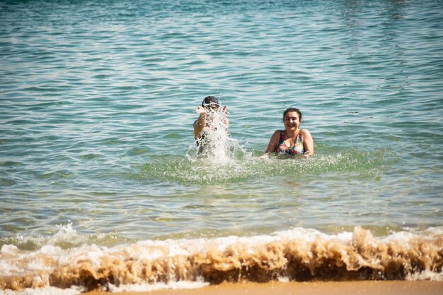 Two women splashing water on the beach at porto da barra in salvador bahia