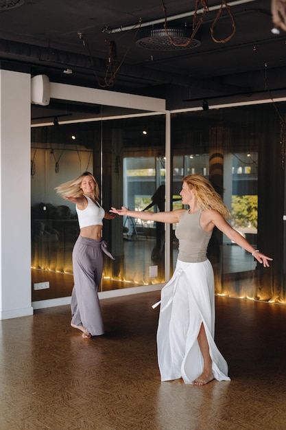 Two women in sportswear are doing dance yoga in the gym