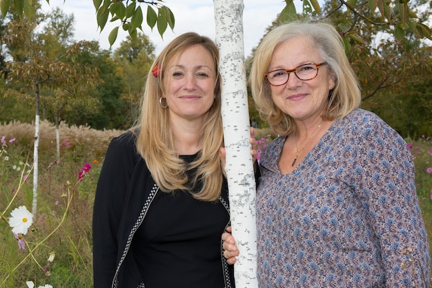 Two women standing outdoors smiling mother and daughter