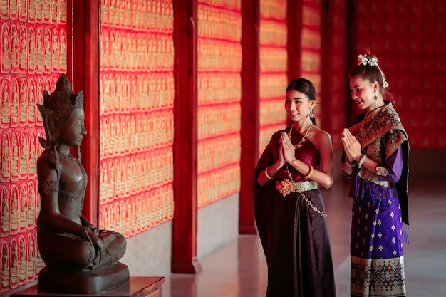 Two women in Thai national costumes and Lao national costume while visiting tourist attractions in Thailand