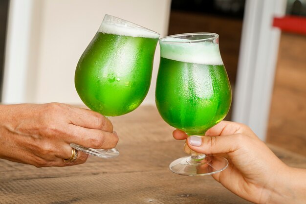 Two women toasting St. Patricks Day, on wooden table.