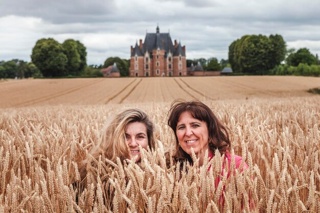 Two women travelers in a field of wheat ears in front of a renaissance castle