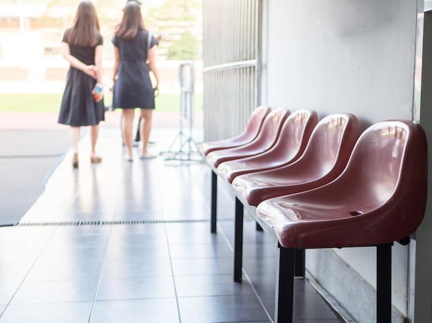 Two women walk through the hallway with red chairs