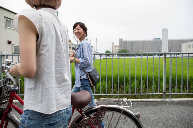 Photo two women walking along a footpath pushing a bicycle