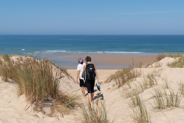 Two women walking sand dune beach go to ocean atlantic sea in\
cap ferret france