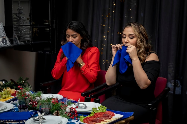 Two women wiping their mouths with a napkin at a christmas dinner