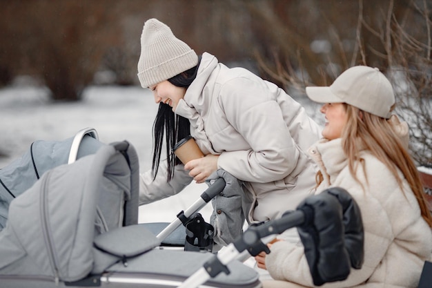 Two women with baby strollers sitting on a bench and
talking