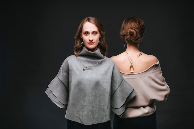 Two women with handmade jewelry on black background