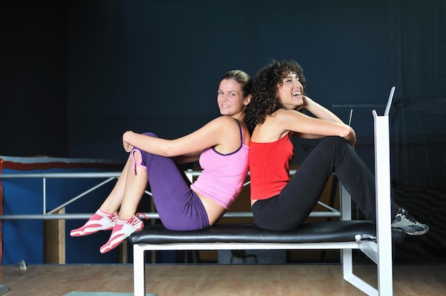 две женщины тренируются и растягиваются в фитнес-клубе