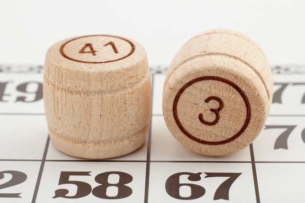 Two wooden barrel numbers and card for a lotto game on a white background. Close-up view