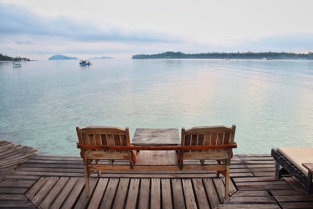 Two wooden chair on wooden floor with blue sea background