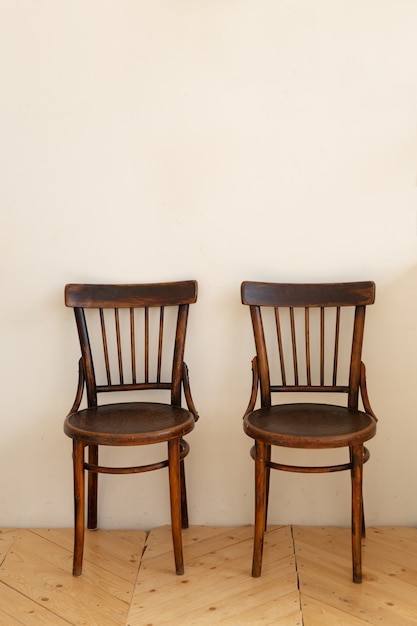 Two wooden chairs and white wall background