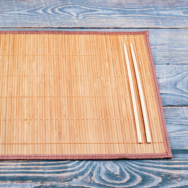 Photo two wooden chopsticks on a bamboo mat