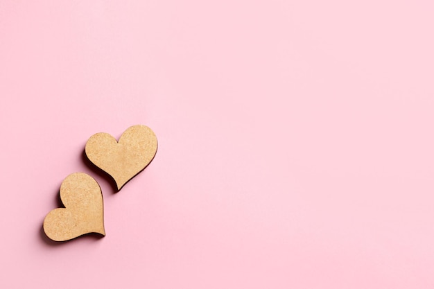 Two wooden hearts on color background