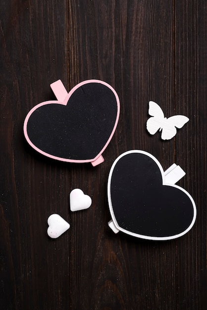 два деревянных сердца с бабочкой на деревянном фоне.