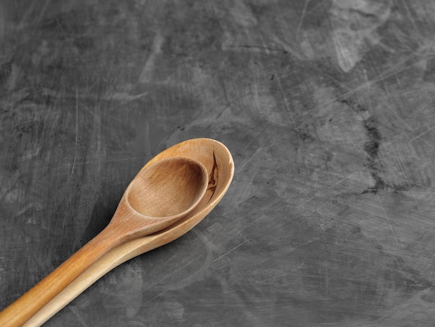 Two wooden spoons lie on a gray table top view.