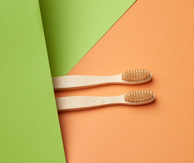 Foto due spazzolini da denti in legno su uno sfondo verde arancione concetto di rifiuto della plastica zero rifiuti