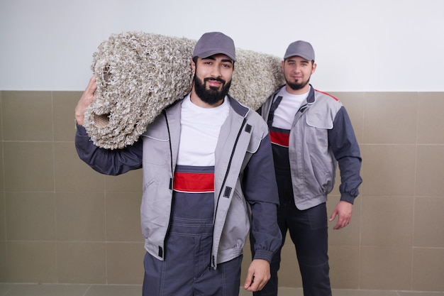 Two workers carrying big carpet after washing service