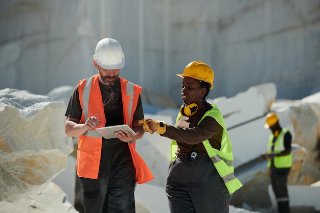 Two workers of factory situated on territory of marble quarry having discussion