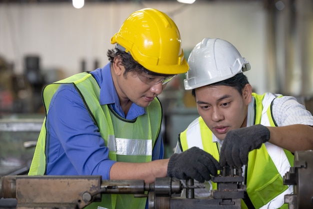 Two workers in production plant as team discussing, industrial scene in background, working together manufacturing activities