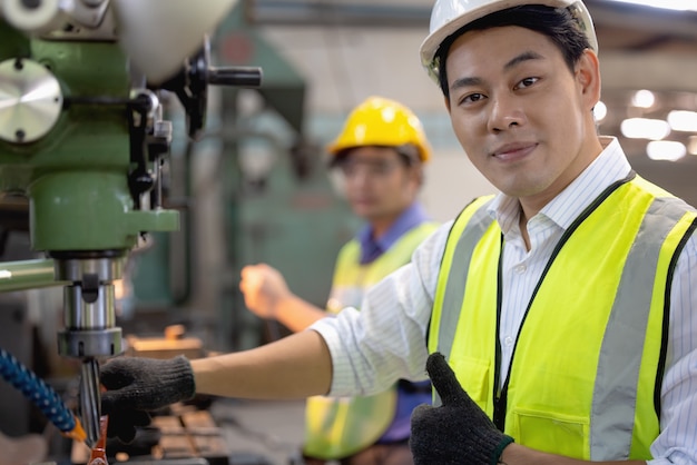 Foto due operai nello stabilimento di produzione come squadra che discute, scena industriale in background, che lavorano insieme alle attività di produzione