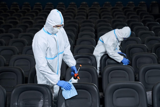 Due lavoratori che puliscono le sedie con disinfettanti al cinema