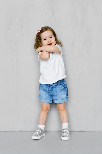 Two years old girl in t-short and jeans shorts posing in studio