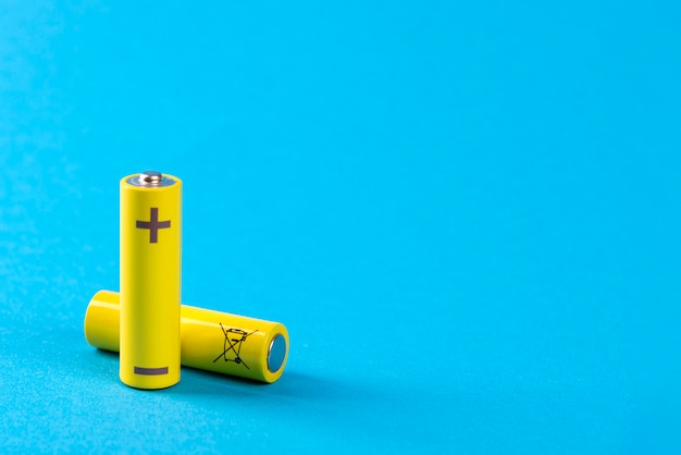 Two yellow batteries on blue with place for text