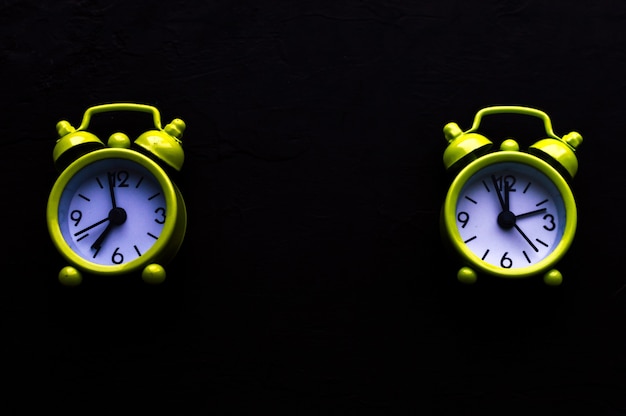 Two yellow bright alarm clock on black background. Free space. Concept morning