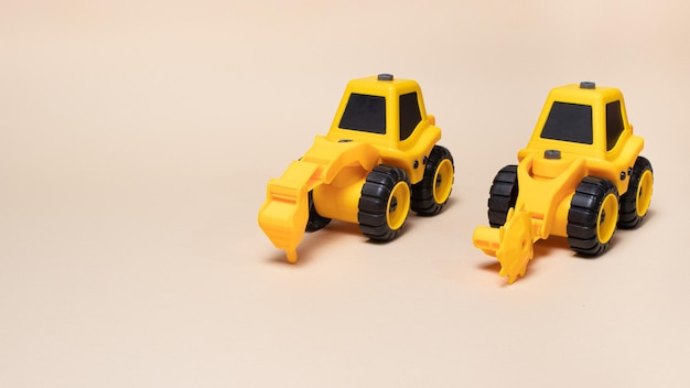 Two yellow construction tractors on a light beige background