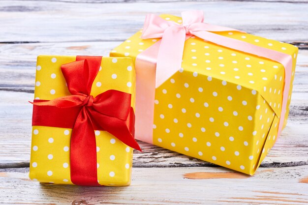 Two yellow gift boxes, wooden background.