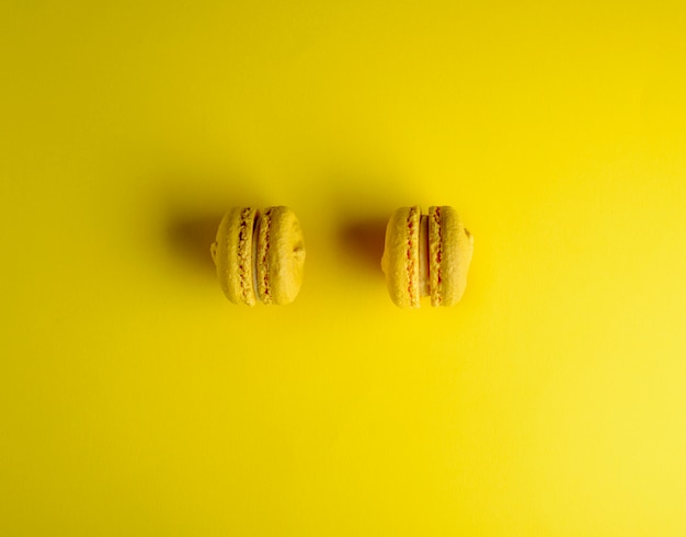 Two yellow macarons on a yellow background