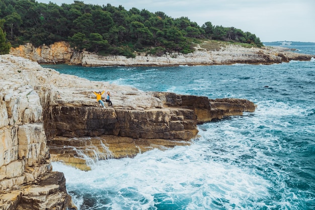 Two young adult women at cliff looking at storm sea