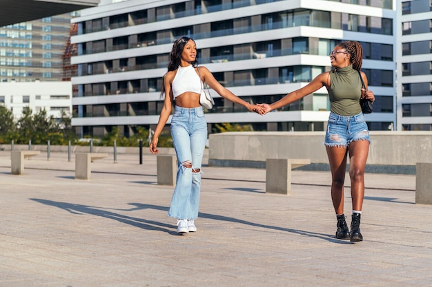 Two young african girls strolling through the city holding hands, concept of friendship and urban lifestyle